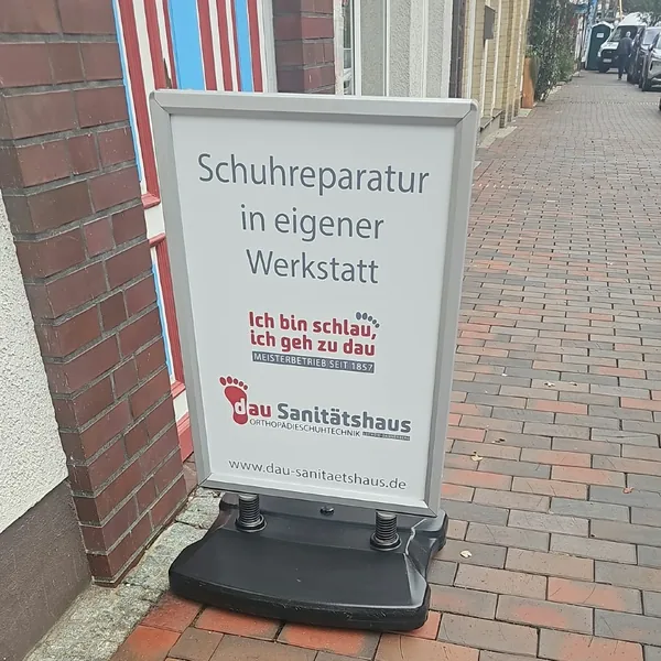 Weißer Kundenstopper „Schuhreparatur in eigener Werkstatt“ vor der Ladentür in der Langen Straße