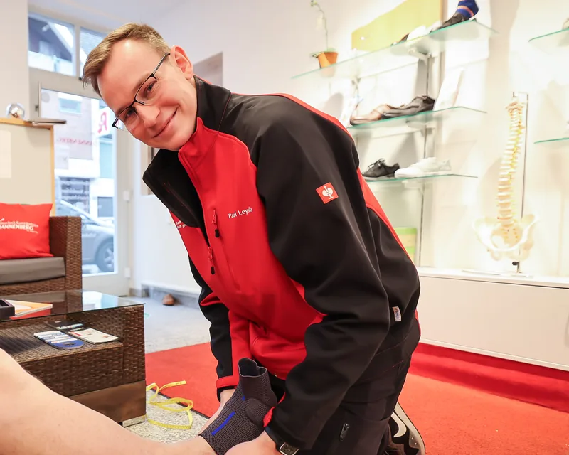 Paul Leyske kniet im Laden und legt einem Kunden eine Sprunggelenkbandage an