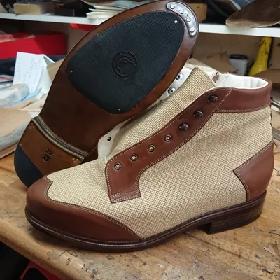 Maßgefertigter Schnürstiefel aus braunem Leder und hellem Leinen, daneben die Ledersohle