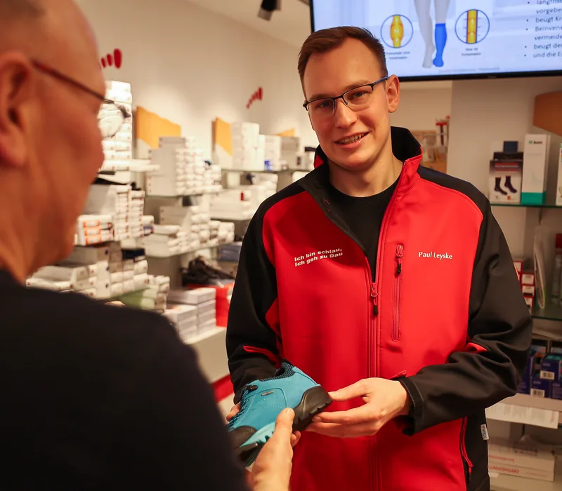 Paul Leyske reicht einem Kunden am Tresen einen Schuh