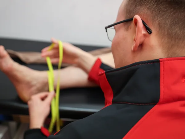 Paul Leyske misst mit einem gelben Maßband das Bein über dem Knöchel