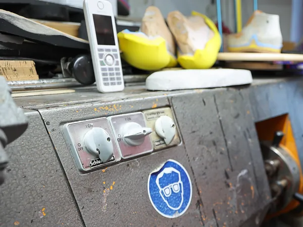 Ein Telefon liegt griffbereit auf der Schleifmaschine in der Werkstatt